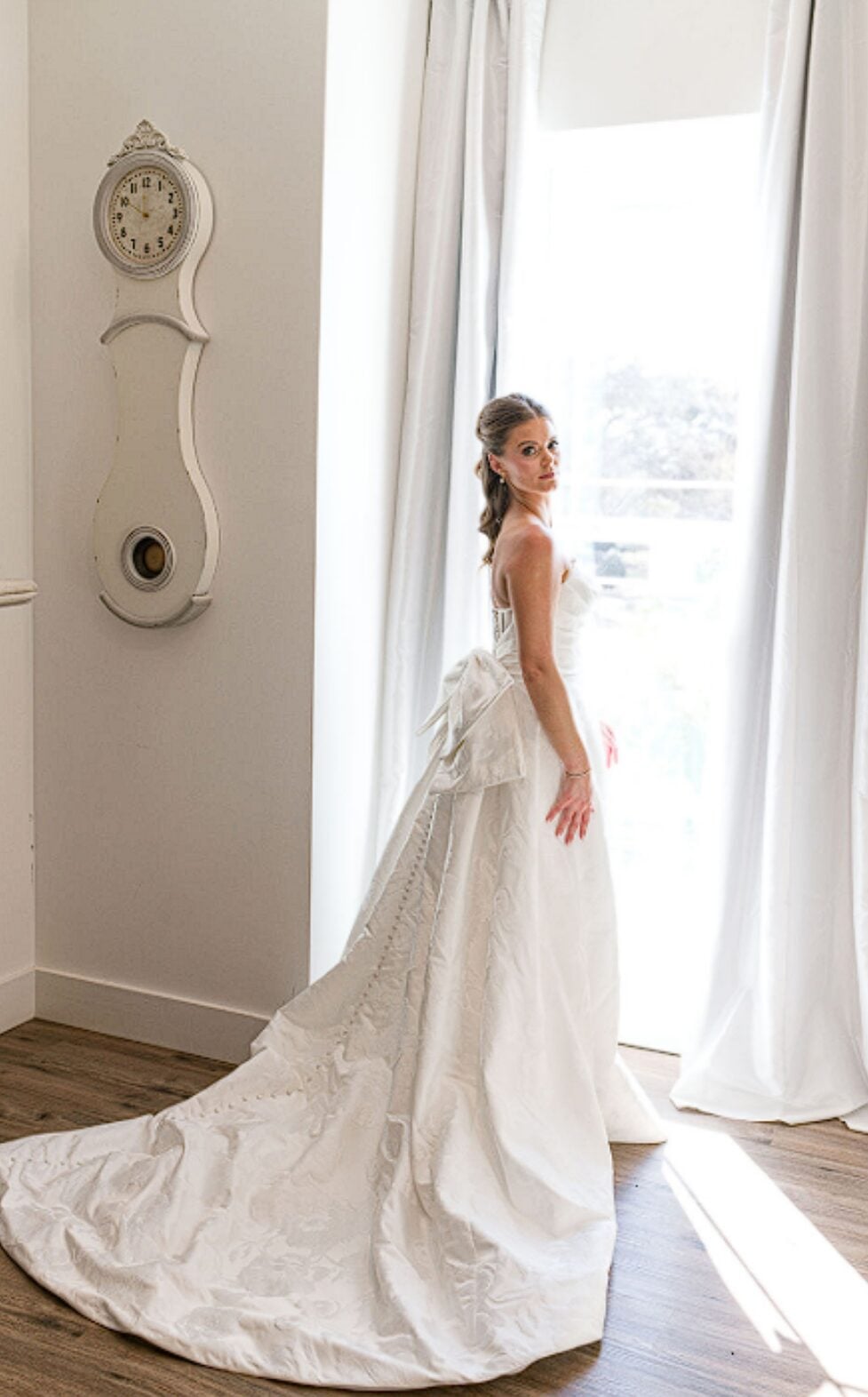 Alexis in her wedding gown beside a sunlit window