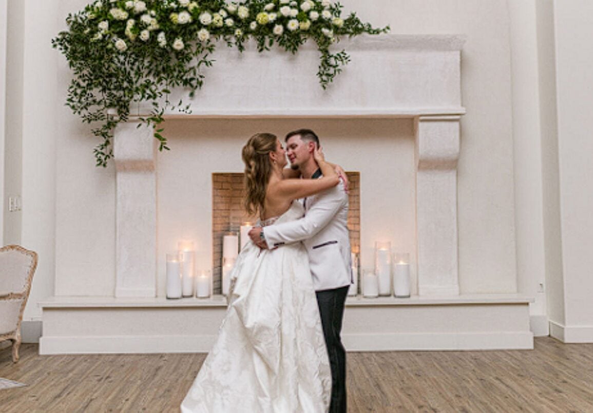 Alexis and Tristan dancing in front of a fireplace decorated with greenery