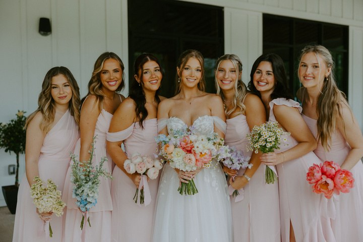 Avery with her bridesmaids holding colorful bouquets by Boxwood Flowers