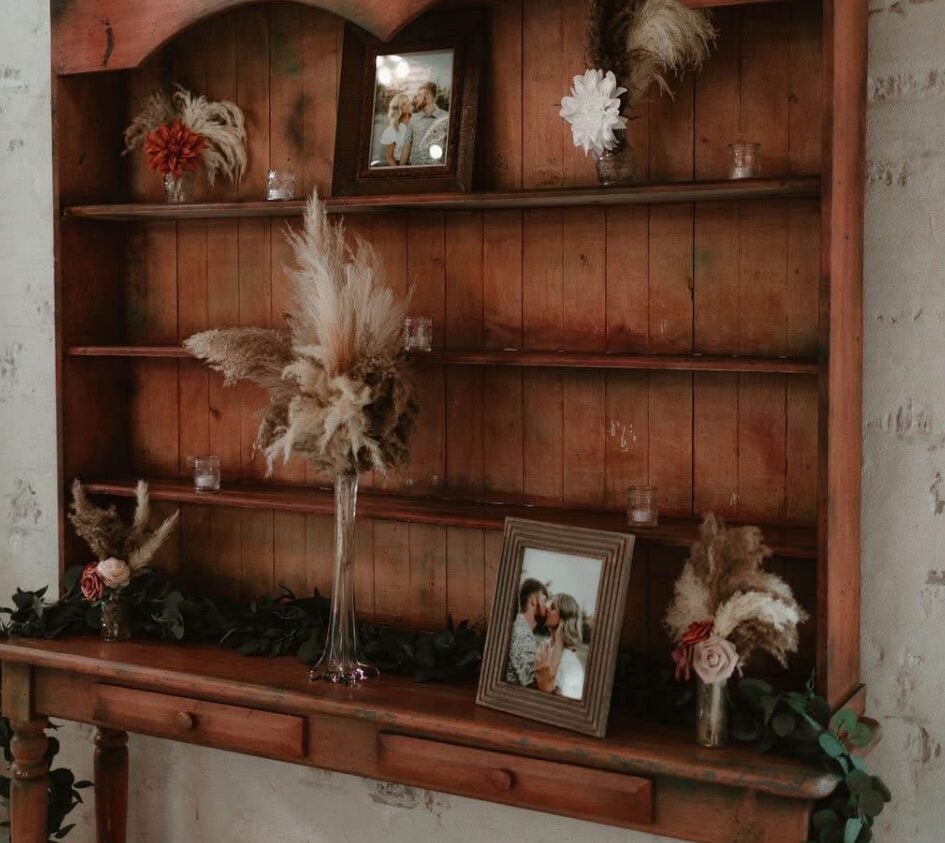 Boho dried floral and pampas decor on a wooden hutch at Cydney and Jaden wedding