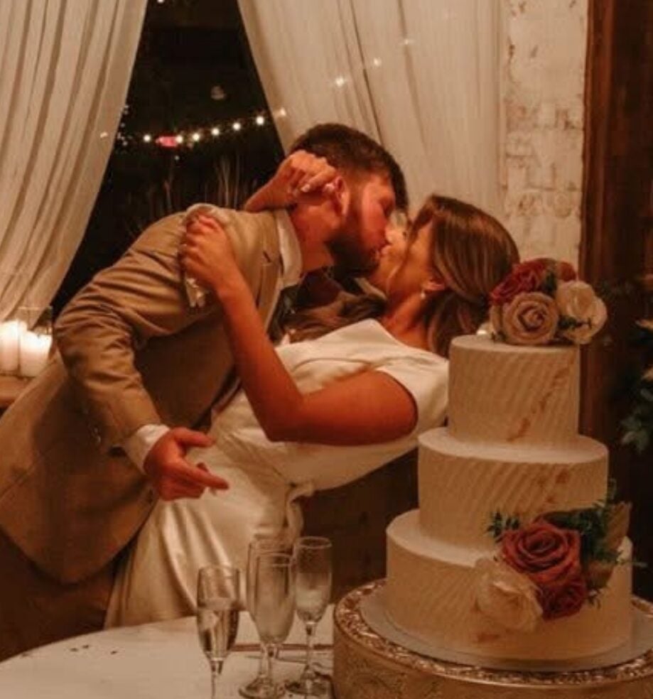 Cydney and Jaden sharing a kiss beside their wedding cake