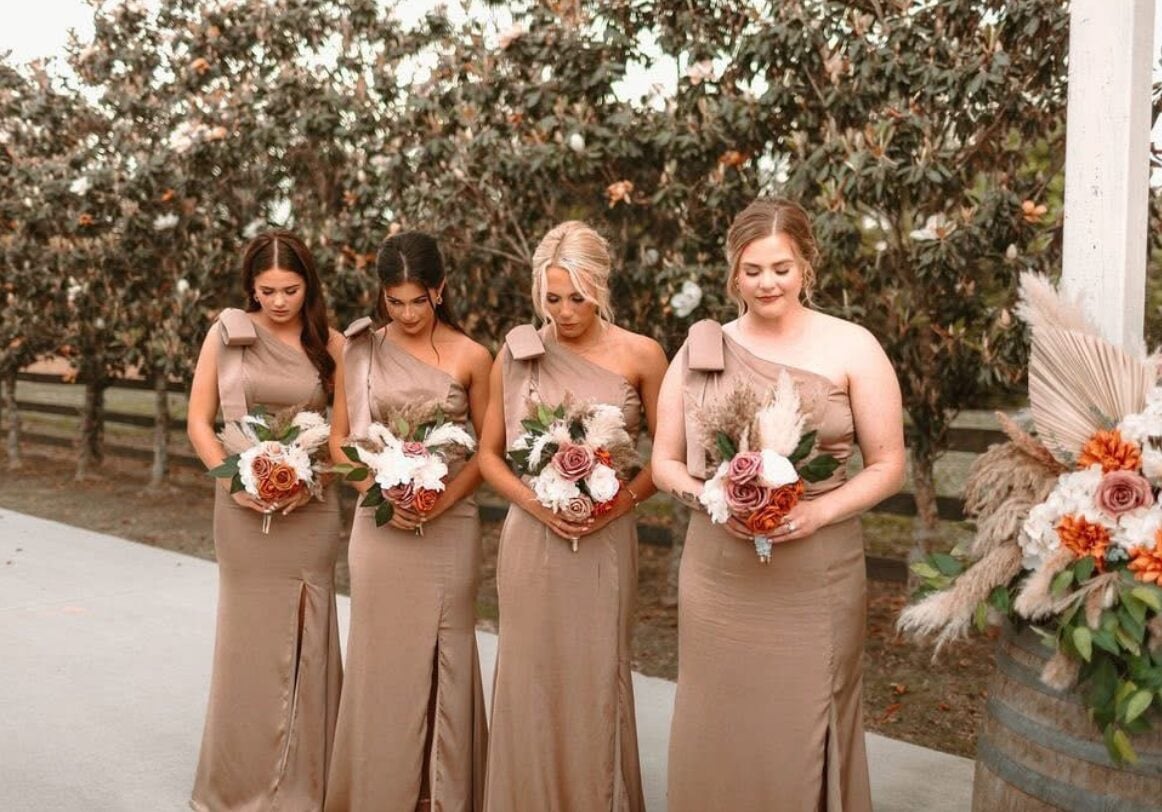 Cydney bridesmaids in neutral dresses holding burnt orange bouquets