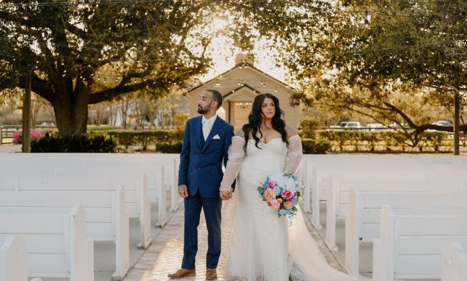Keri and Brandon standing among white pews at The Greenery