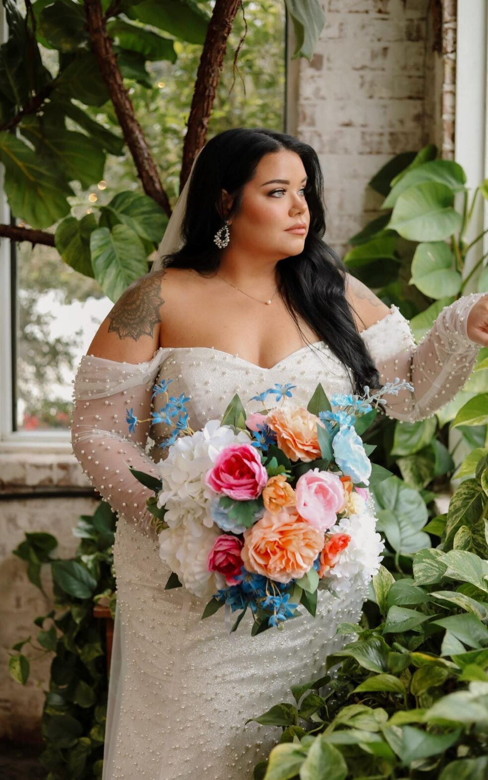 Keri in her wedding gown with a colorful bouquet among greenery